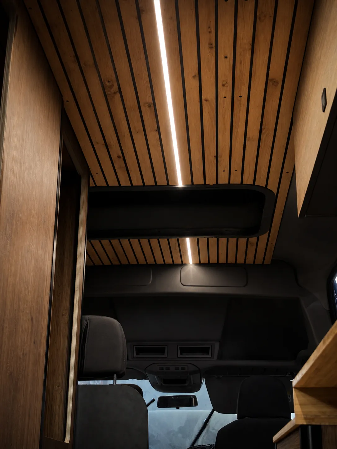 Techo de listones de madera con tira LED lineal y hueco de claraboya, visto desde la cabina